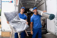 two men in blue shirts and hats are holding up the back of a moving truck