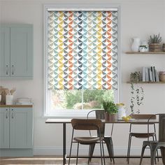 a dining room table with chairs and a window covered in colorful roman blind blinds over the windows