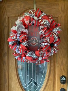 a red and white wreath is hanging on the front door to welcome someone in town