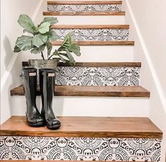 a pair of rubber boots sitting on top of a set of stairs next to a potted plant