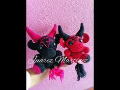 two crocheted devil dolls sitting next to each other on a pink wall background