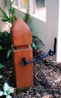 a wooden post with an iron hook attached to it in front of a door way