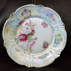 a plate with flowers painted on it is sitting on a black surface and has a string attached to the edge