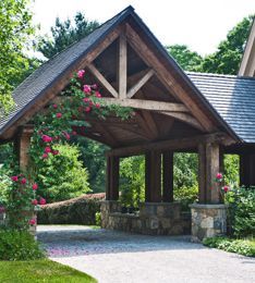 a wooden gazebo surrounded by lush green trees and shrubs with pink flowers on it