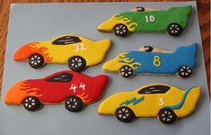 decorated cookies in the shape of race cars on a sheet of paper with blue and yellow icing