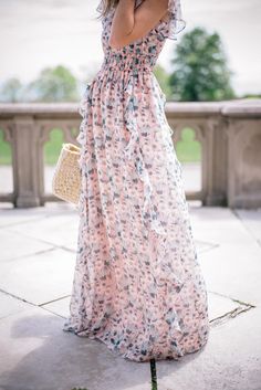 a woman in a long dress is holding an umbrella and talking on her cell phone