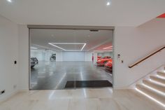 an empty garage with several cars parked in the area and stairs leading up to it