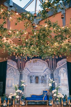 a stage set up for a wedding with flowers and greenery hanging from the ceiling