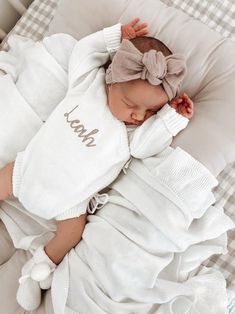 a baby is sleeping in a white outfit with a bow on it's head