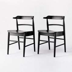 two black chairs sitting next to each other on a white surface with no one in it