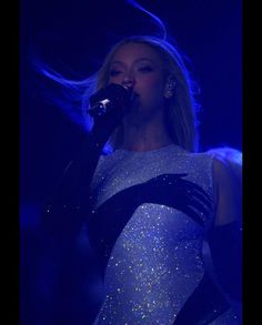 a woman in a white and black dress singing into a microphone