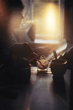 the person is preparing food on the table in the dark room with sunlight coming through the window