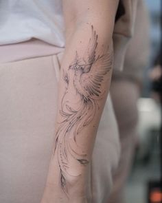 a woman's arm with a bird tattoo on the left side of her arm