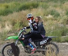 a woman sitting on top of a dirt bike next to a person wearing a helmet