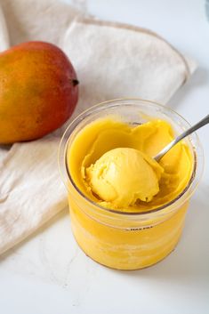 a glass jar filled with mango ice cream next to a pomegranate on a napkin