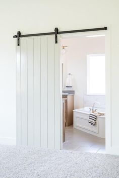 an open door leading to a bathroom with a sink and bathtub in the background