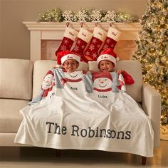 two children laying in bed under christmas stockings