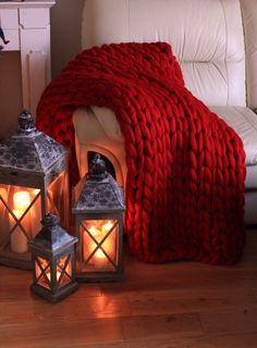 two lit candles sitting next to a red blanket