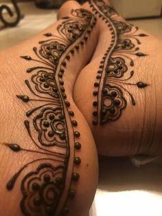 two legs with henna tattoos on them and one is showing off the intricate design