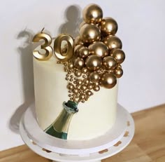 a white cake with gold decorations and a wine bottle on the top that says 30th