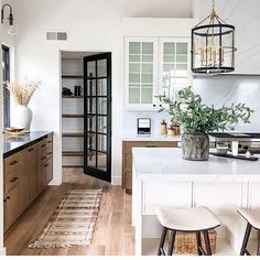 a kitchen with white walls and wooden floors, two stools on the counter top