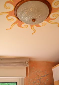 the ceiling light is hanging from the ceiling in the room that has been painted orange and yellow