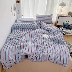 an unmade bed with blue and red striped sheets