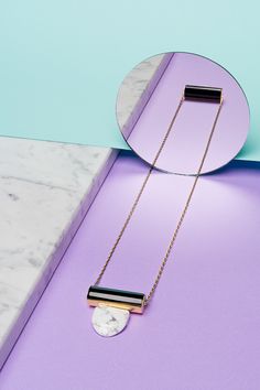 a necklace with a marble disc on it and a mirror in the corner behind it