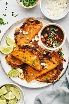 mexican food on a plate with salsa and limes