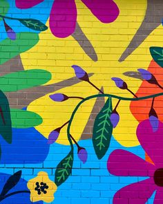 a painted mural on the side of a brick building with flowers and leaves in bright colors