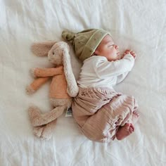 a baby laying on top of a bed next to a stuffed animal