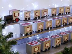 a display case filled with lots of toy train cars next to christmas tree branches and lights