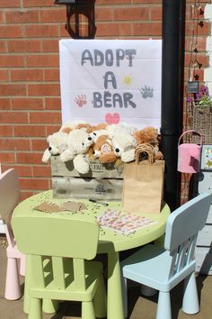 there is a table with stuffed animals on it and a sign that says adopt a bear