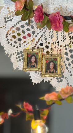 two framed pictures are hanging on a lace doily with pink flowers in the background