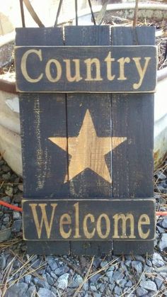 a wooden sign that says country welcome with a gold star on it sitting in the gravel