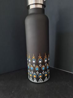 a black and silver water bottle sitting on top of a counter next to a wall