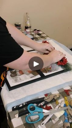 a woman is making a christmas wreath on a table with scissors and other crafting supplies