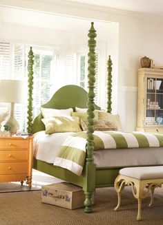 a green and white bedroom with four post bed, dresser, mirror and chest of drawers