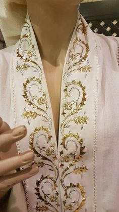 a woman's white shirt with gold trimmings