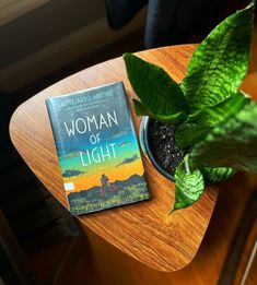 a book sitting on top of a wooden table next to a potted green plant