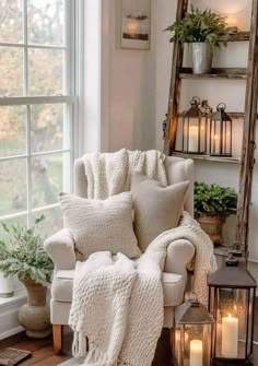 a living room with white furniture and candles on the windowsill, in front of a window