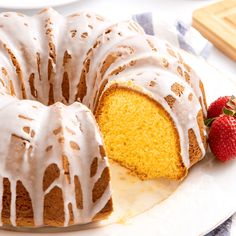 a bundt cake with icing and strawberries on the side