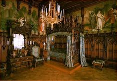 an ornately decorated bedroom with chandelier and paintings on the wall behind it