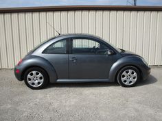 a small gray car parked in front of a metal building with no doors on it