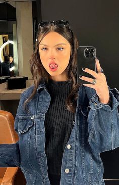 a woman taking a selfie in front of a mirror with her cell phone up to her ear