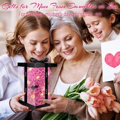 two women and a girl are holding a pink box with flowers in it that says, gifts for mom from daughter on her birthday