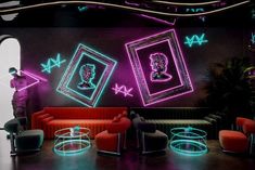 a living room with neon lights and pictures hanging on the wall, in front of a man standing next to a couch