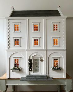 a white doll house sitting on top of a wooden table