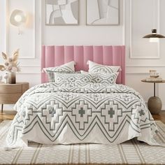 a bed with pink headboard and pillows in a white room next to two pictures on the wall