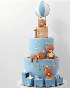 a three tiered blue cake with teddy bears on the top and stars around it